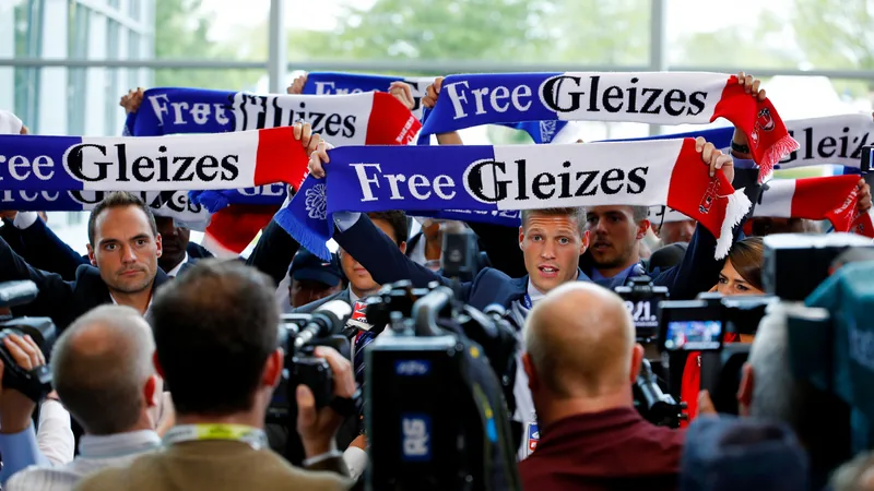 Journalists hold up scarves reading 'Free Gleizes' at a France World Cup press conference to demand the release of imprisoned French sports