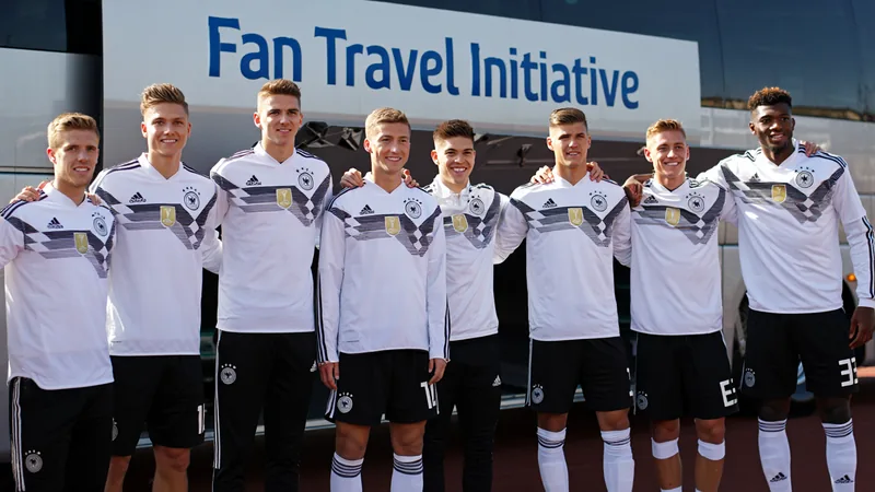 German national team players in their World Cup kits, with a bus in the background, symbolizing the funded fan travel initiative.