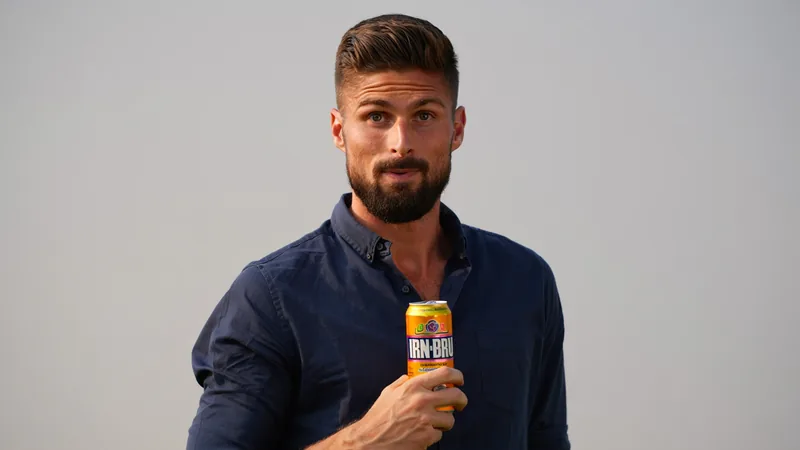 Olivier Giroud holding a can of Irn-Bru with a surprised expression