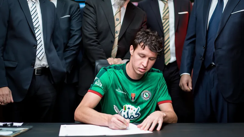 Jack Hendry in Al-Ettifaq kit, signing a new contract with club officials.
