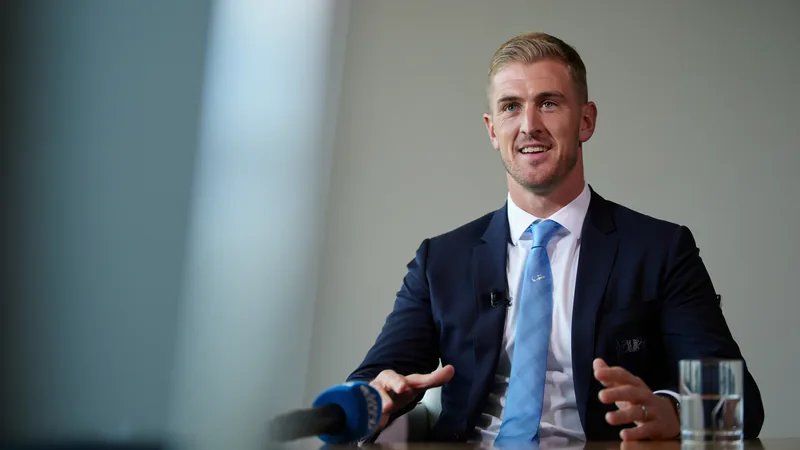 Joe Hart: England must 'dare to dream' ahead of Euro 2024 Joe Hart, former England goalkeeper, speaking in an interview, wearing a suit and smiling.