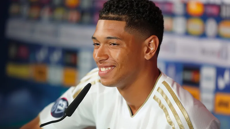 Bellingham praises Real Madrid's new signings Jude Bellingham in a Real Madrid jersey, smiling during a press conference.