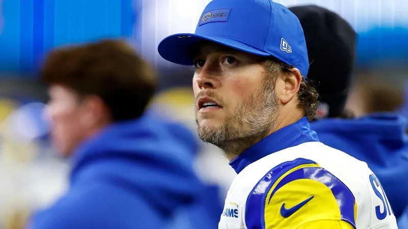 Matthew Stafford, quarterback for the LA Rams, speaking at SoFi Stadium during the FIFA World Cup, with a crowd in the background.