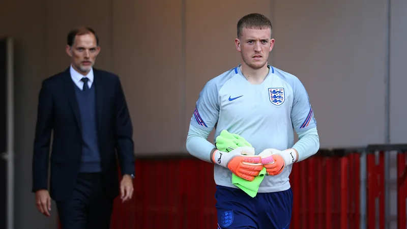 Jordan Pickford in England goalkeeper kit, looking focused, with Thomas Tuchel in background — latest news and analysis.