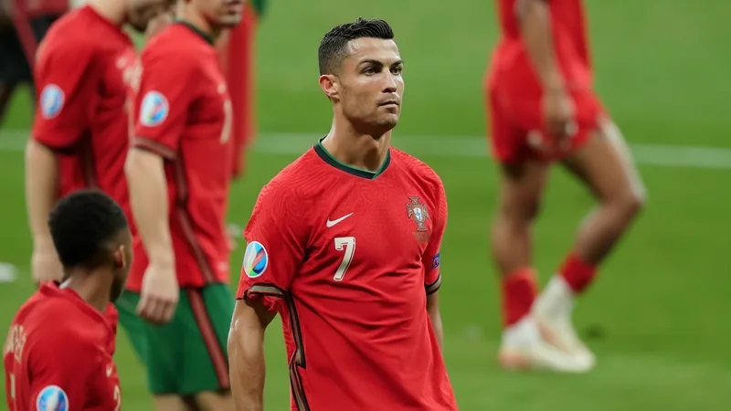 Cristiano Ronaldo in Portugal national team jersey, looking contemplative on the pitch, with teammates in background. — latest news and analysis.