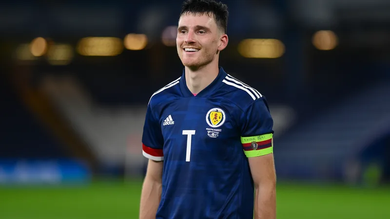 Robertson: Scotland's World Cup Dream and Brazil Clash Andy Robertson in Scotland kit, smiling, with a football pitch in the background, representing his role as captain for the 2026 World Cup.