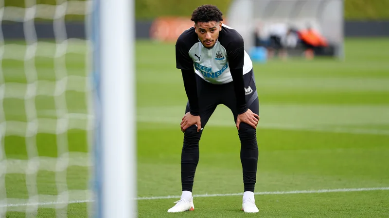 Tino Livramento in Newcastle United kit, looking concerned after an injury during training.