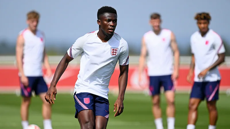 Tuchel: England managing Saka's fitness ahead of World Cup Bukayo Saka in England training kit, focused during a drill, with teammates in background.