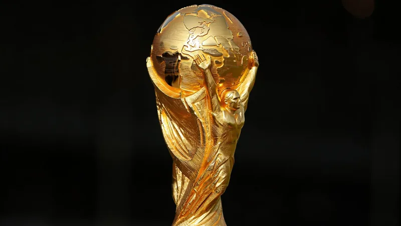 The current FIFA World Cup trophy, a gold statue of two human figures lifting Earth, on a dark background. — latest news and analysis.