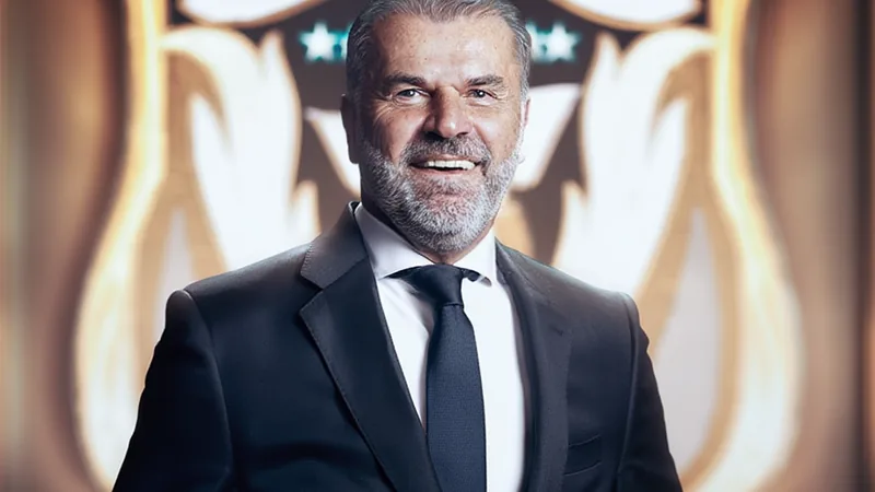 Ange Postecoglou signs two-year deal as Al Nassr head coach Ange Postecoglou smiling in a suit, standing in front of Al Nassr logo