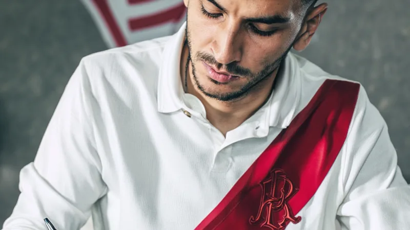 Ángel Correa in River Plate jersey, signing contract, with club logo in background.