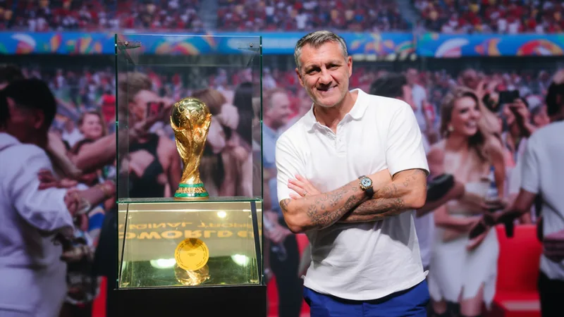 FIFA Block Party at Fanatics Fest Draws Stars Crowd at Fanatics Fest watching FIFA World Cup final on large screen, with trophies on display and celebrities mingling.