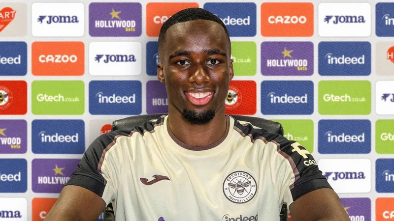 Michael Kayode signs new Brentford contract until 2032 Michael Kayode signing a contract at Brentford's stadium, with his agent Giuseppe Pesce looking on. — latest news and analysis.