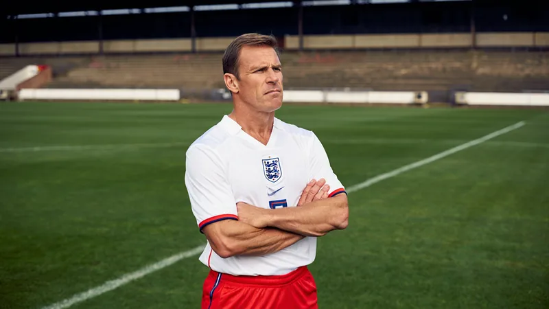 Shearer: '98 pain lingers but England can rewrite history Alan Shearer in England kit, looking pensive, with a football pitch in the background, representing his reflection on the 1998 World Cup defeat.