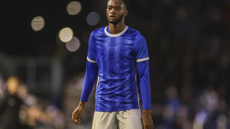 Abu Kamara in a football kit, with a stadium background, symbolizing his return to Portsmouth. — latest news and analysis.
