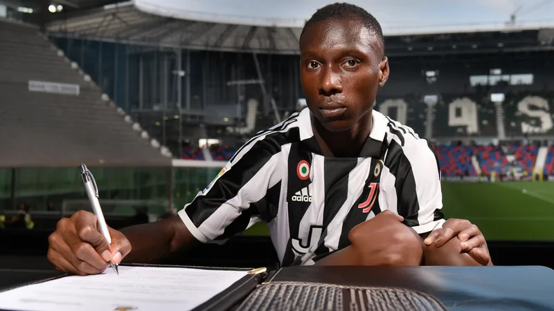Kolo Muani to Juventus: Permanent Deal Agreed Randal Kolo Muani in Juventus jersey, signing contract, with stadium background.