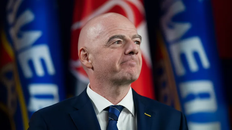 FIFA President Gianni Infantino at a press conference, with UEFA flags in the background.