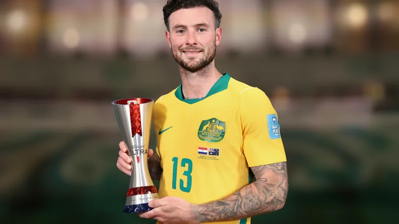 Aiden O’Neill im australischen Trikot auf dem Spielfeld, der den Ball kontrolliert, mit konzentriertem Blick und dynamischer Körperhaltung.