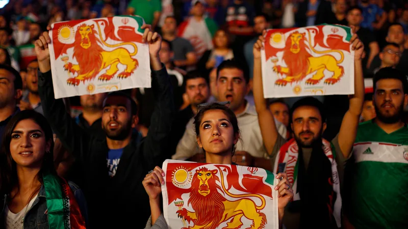 Iranische Fans in Los Angeles halten eine vorrevolutionäre iranische Flagge mit Löwe und Sonne hoch, während im Hintergrund ein Fußballstadion zu
