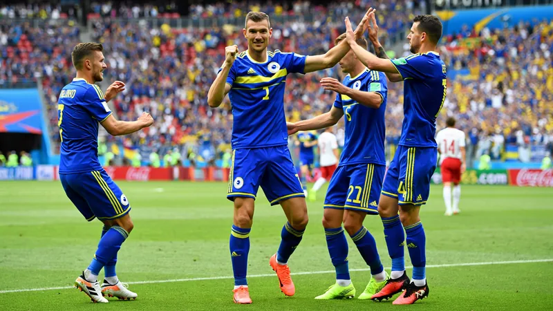 Džekos letzter Tanz könnte Bosniens Neuanfang sein — Football World Edin Džeko im Trikot der bosnischen Nationalmannschaft, jubelnd nach einem Tor, im Hintergrund die Flagge Bosnien-Herzegowinas.