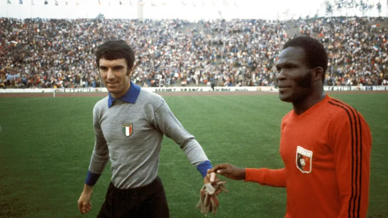 Haiti schockt Italien bei der WM 1974 — Football World Cup News Haitianische Spieler jubeln nach dem Tor von Emmanuel Sanon im Münchner Olympiastadion, während italienische Spieler enttäuscht dreinschauen.