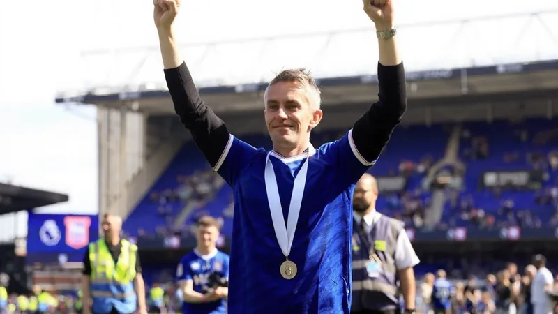 Kieran McKenna verlässt Ipswich Town und legt Fußballpause ein Kieran McKenna in Trainingskleidung an der Seitenlinie eines Fußballplatzes, im Hintergrund das Stadion von Ipswich Town