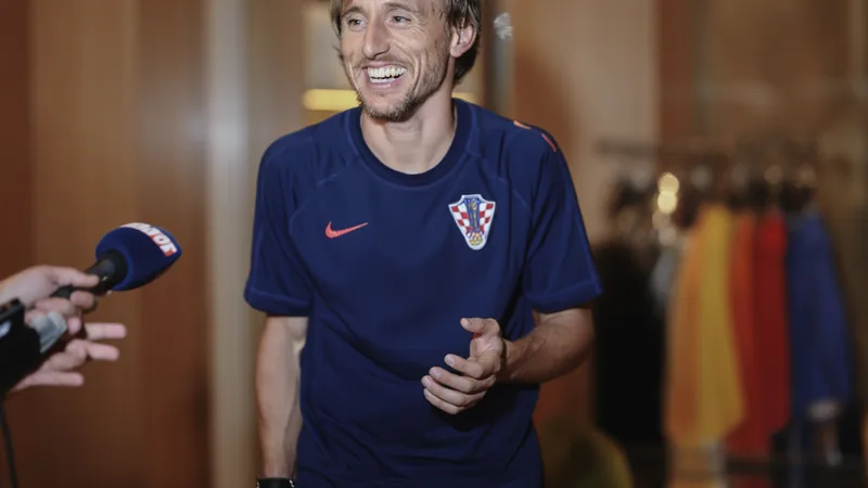 Luka Modrić im Trikot von Real Madrid lächelt während eines Interviews, im Hintergrund das Stadion Santiago Bernabéu. — latest news and analysis.