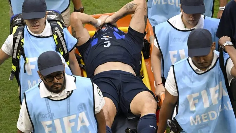 Manuel Ugarte liegt nach einem Zweikampf im WM-Spiel gegen Spanien schmerzverzerrt auf dem Rasen, während Teamkollegen und Sanitäter herbeieilen.