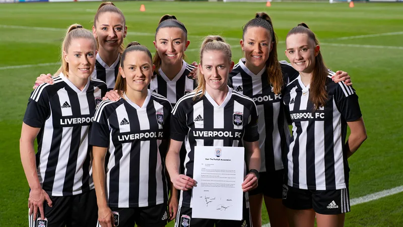 National-League-Klubs fordern FA zur Aufgabe von Akademie-Plänen auf Ein Fußballplatz mit einem Frauenfußballspiel, im Hintergrund ein Stadion, Spielerinnen in Trikots, eine Trainerin am Spielfeldrand mit Notizblock