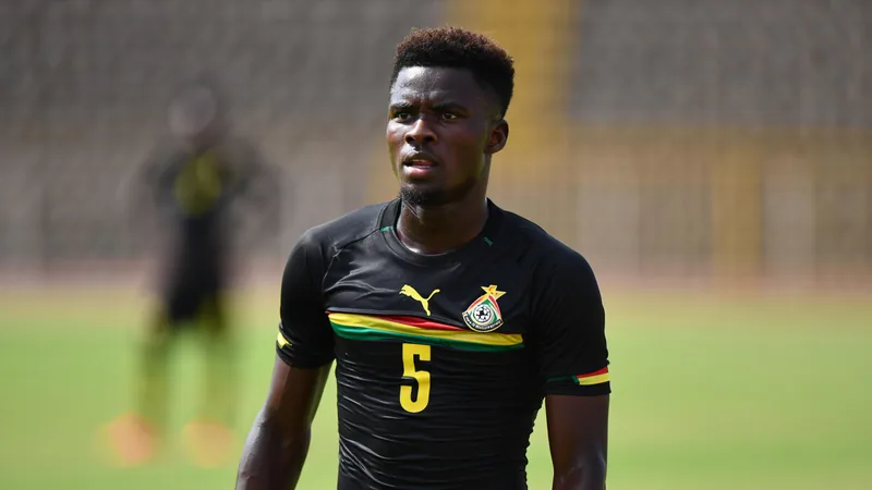 Partey täuschte kanadische Behörden über frühere Festnahme — Football Thomas Partey im Trikot der ghanaischen Nationalmannschaft, der traurig am Spielfeldrand sitzt, während seine Teamkollegen trainieren.