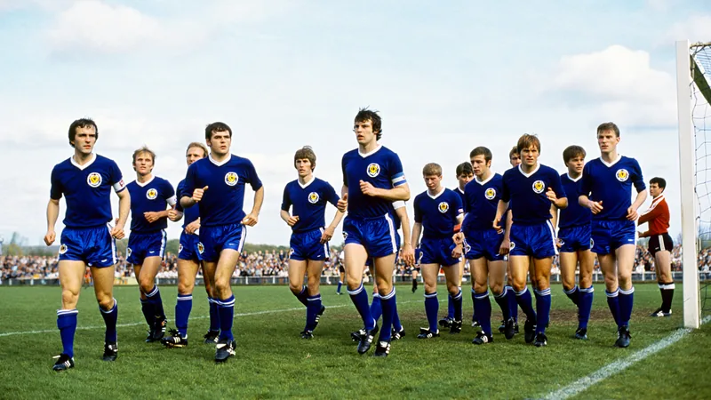 Schottische Fußballspieler in den 1970er Jahren auf dem Spielfeld, enttäuscht nach einem Spiel, mit Zuschauern im Hintergrund.