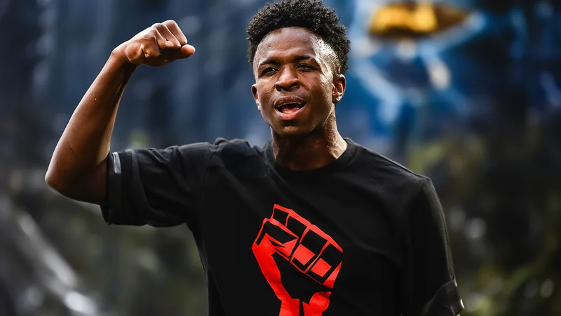 Vinícius Júnior im Trikot von Real Madrid, der mit ernster Miene in die Kamera blickt, im Hintergrund ein Stadion mit Fans.