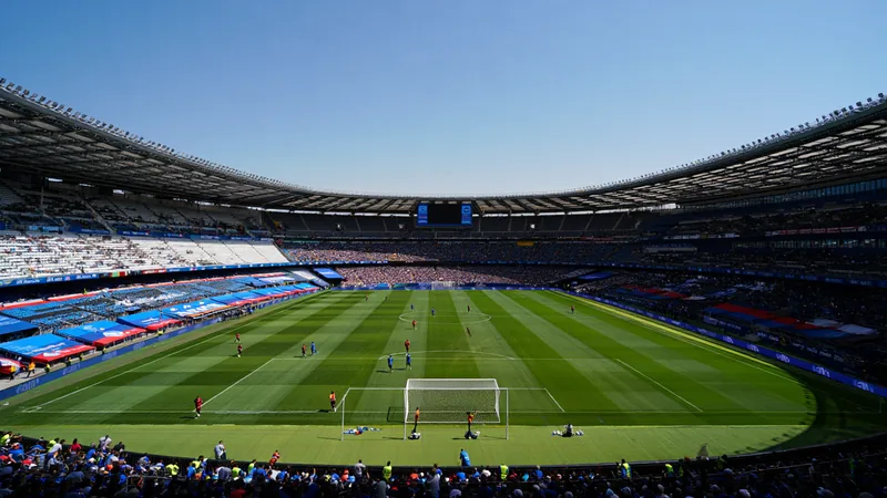 Luftaufnahme des Estadio Azteca in Mexiko-Stadt, umgeben von der Stadt, mit grünem Rasen und leeren Rängen bei Tageslicht.