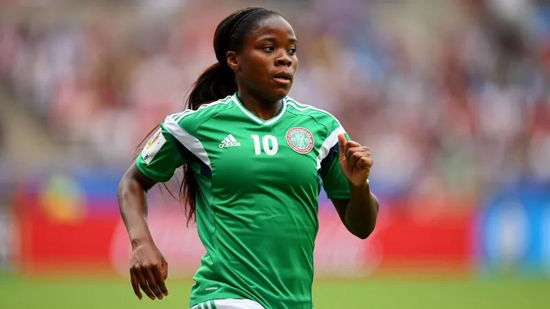 Ngozi Okobi-Okeoghene: Mutterschaft sollte nicht das Ende sein Ngozi Okobi-Okeoghene im nigerianischen Trikot auf dem Fußballplatz, mit ihrem Sohn auf dem Arm, lächelnd in die Kamera.