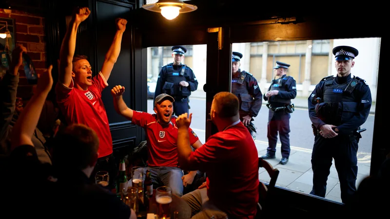 Polizeichef appelliert an England-Fans in der Heimat — Football World Ein britischer Polizist in Uniform spricht in ein Mikrofon vor einer Menschenmenge von Fußballfans mit England-Fahnen. — latest news and analysis.