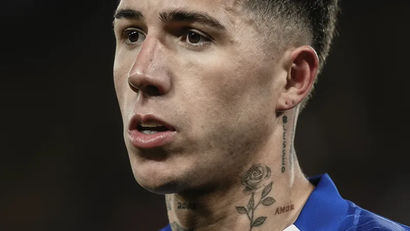 Real Madrid dementiert Interesse an Enzo Fernández — Football World Enzo Fernández im Chelsea-Trikot läuft auf dem Rasen eines vollen Stadions, während er den Ball kontrolliert und Gegner im Hintergrund sind.