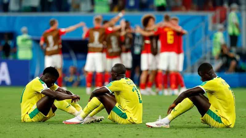 Senegals dramatischer WM-Aus: Spätestes Tor und VAR-Kontroverse Senegals Spieler liegen enttäuscht auf dem Rasen, während Belgiens Youri Tielemans den Siegtreffer per Elfmeter bejubelt, im Hintergrund die