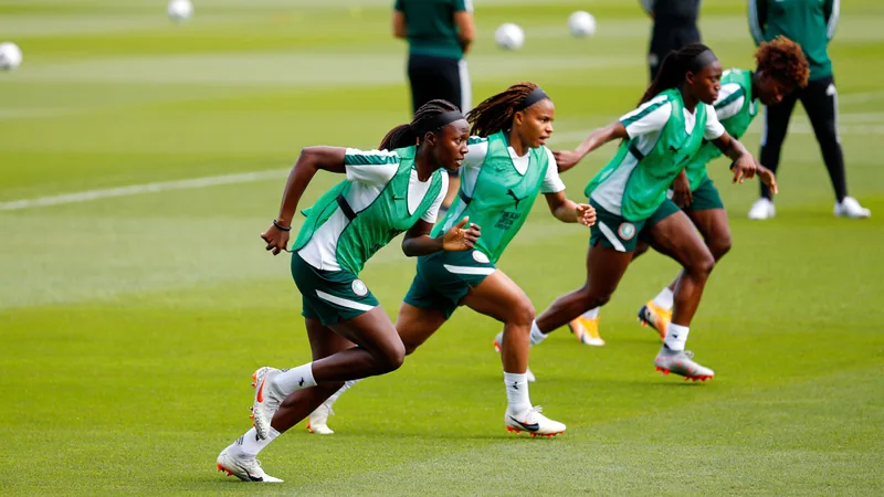 Nigerianische Super Falcons in grünen Trikots feiern auf dem Rasen mit dem Wafcon-Pokal, im Hintergrund ein volles Stadion in Marokko.
