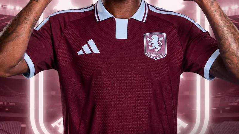 Aaron Wan-Bissaka im Aston-Villa-Trikot neben dem Vereinswappen auf einem Rasen, im Hintergrund das Stadion von Villa Park in Birmingham.