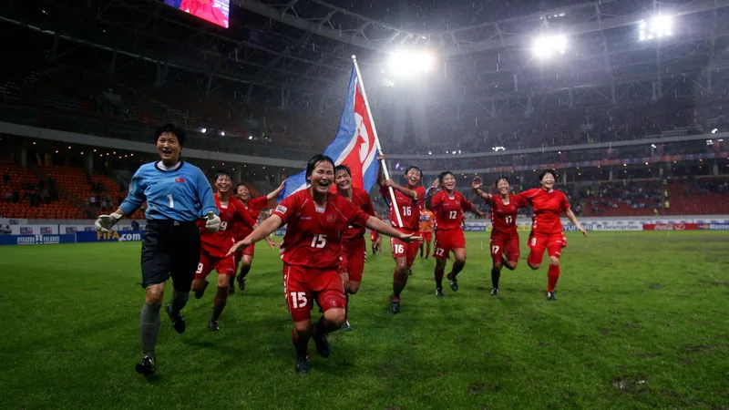U-20-Frauen-WM: Debütanten-Bilanz — Football World Cup News Junge Fußballspielerinnen in den Trikots verschiedener Nationen laufen gemeinsam auf ein Stadion zu, während im Hintergrund die Flaggen der