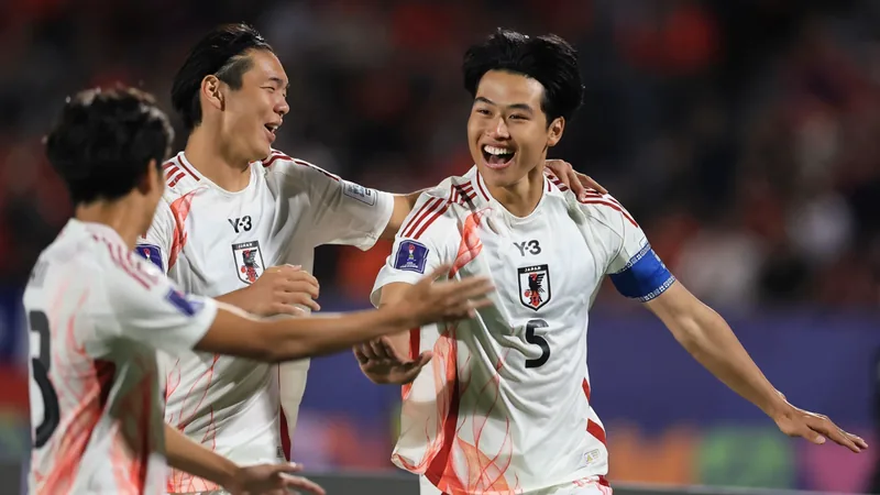 FIFA: Sieben Talente für Japans neue Ära — Football World Cup News Junge japanische Fußballspieler in Nationaltrikots trainieren auf einem Platz, im Hintergrund die Skyline von Tokio bei Sonnenuntergang.