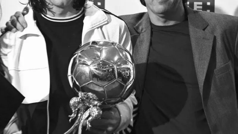 Jorge Messi, Vater von Lionel Messi, verstorben — Football World Cup Jorge Messi, Vater von Lionel Messi, in einem dunklen Anzug, neben seinem Sohn auf einem Fußballplatz, mit trauernder Miene und Händen in den Taschen.