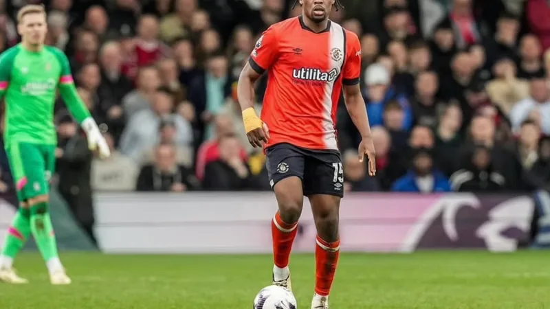 Mengi-Wechsel: Luton erlaubt Gespräche — Football World Cup News Teden Mengi im Trikot von Luton Town während eines Spiels, im Hintergrund die Stadiontribüne mit Fans. — latest news and analysis.