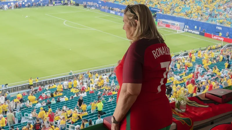 Dolores Aveiro, madre de Cristiano Ronaldo, sonriendo en un evento familiar con su hijo, ambos vestidos elegantemente, fondo de una sala iluminada.