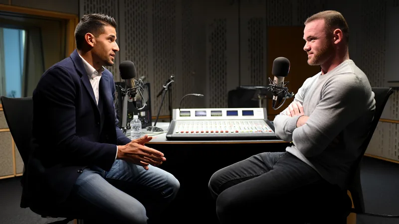 El Show de Wayne Rooney: Clichy analiza a Mbappé, Henderson y el caos Wayne Rooney y Gaël Clichy conversan en un estudio de radio con micrófonos y auriculares, con una pantalla mostrando imágenes del Mundial de fútbol.