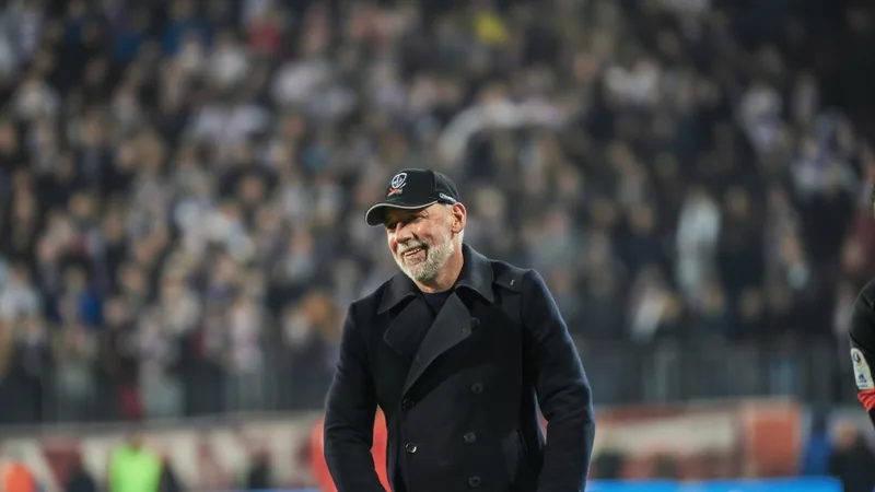 Eric Roy, entrenador del Stade Brest, con camiseta del club en el estadio Francis-Le Blé, con expresión seria y brazos cruzados.
