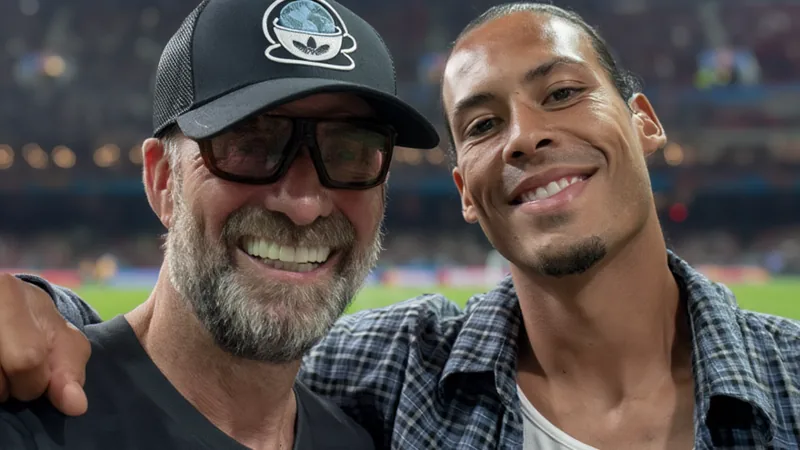 Jürgen Klopp y Virgil van Dijk abrazándose y sonriendo en un evento del Mundial en Estados Unidos, con aficionados al fondo.