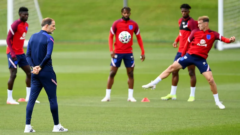 Apuestas defensivas de Tuchel y Alexander-Arnold — Football World Cup Thomas Tuchel, entrenador de Inglaterra, observa el partido desde la banda con expresión seria, mientras los jugadores calientan en el campo.