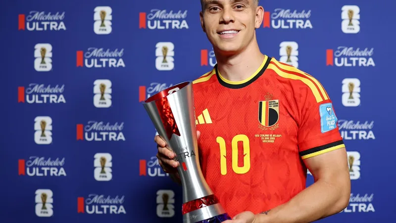 Leandro Trossard celebrando con el trofeo MVP en el campo de fútbol, con la camiseta de Bélgica y el logo de la FIFA al fondo.