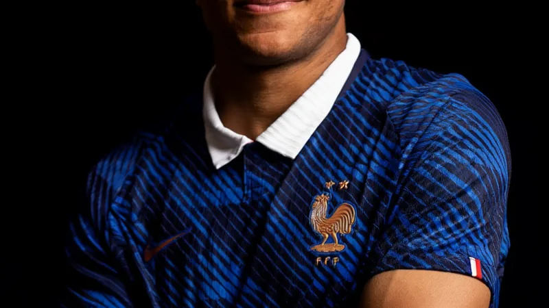 Kylian Mbappé celebrando un gol con la camiseta de la selección francesa, con el número 10, en un estadio lleno de banderas tricolores.